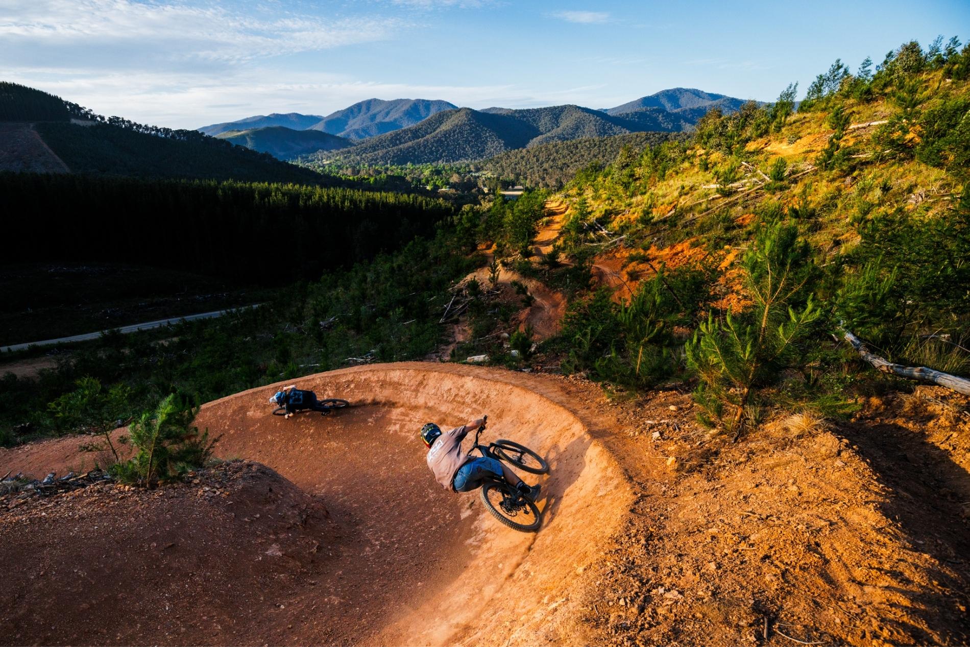 Mountainscape backdrop in Birght Victoria in Mystic Bike Park with two mountain bike riders