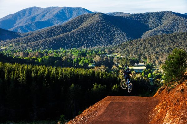 Mountain backdrop in Bright Victoria with a mountain bike rider jumping at mystic bike park