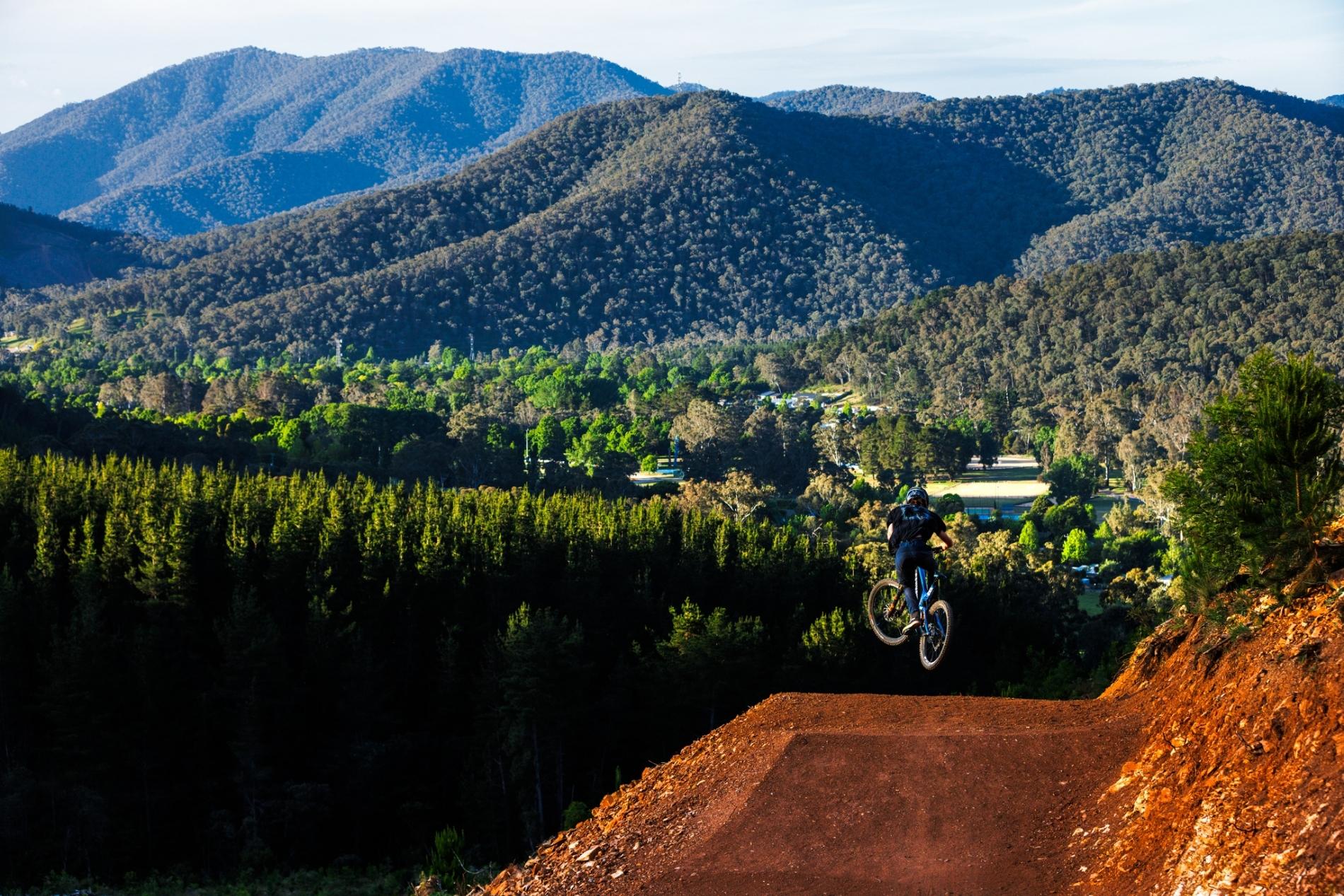 Mountain backdrop in Bright Victoria with a mountain bike rider jumping at mystic bike park