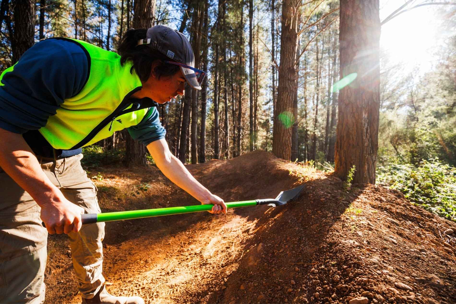 Person in pine forest plantation with shovel in fluro clothes Mystic Bike Park