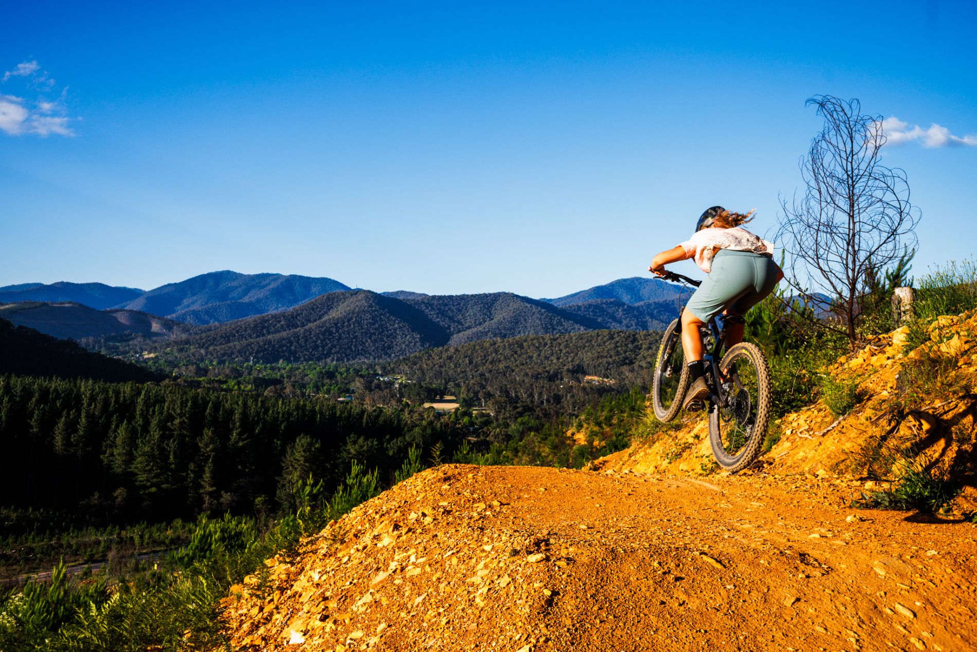 MTB rider with mountain in background jumping bicycle over off road jump