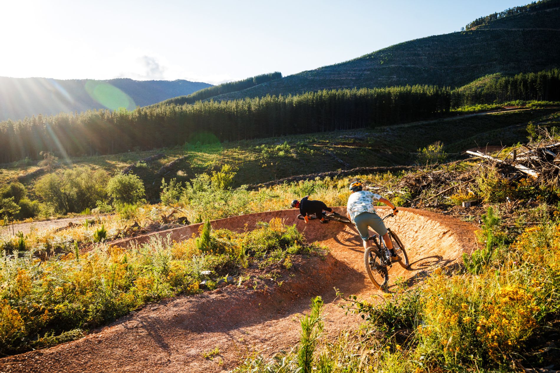 two mtb riders on off road trail in amongst mountain scape backdrop at mystic in bright