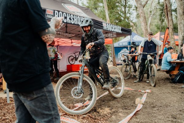Spectators at Gravity Jam Rider in amongst event village at MTB event participating in balancing game at mystic